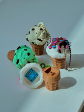 Multiple 3D printed ice cream cone clicker keychains in various flavors including vanilla, chocolate, strawberry, and more, with one cone opened to show the internal key switch mechanism