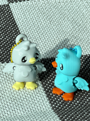 3D printed blue goose and white goose bag charms looking at each other with orange and yellow beaks and feet