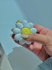 3D printed daisy flower clicker held in a person’s hand, showing its small, portable size and clickable yellow center