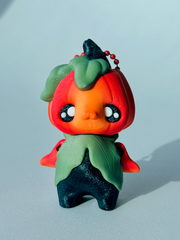 Cute pumpkin-themed bag charm standing on a desk to show articulated limbs and ombré head color.