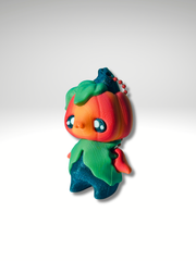 Articulated 3D printed pumpkin pixie charm standing with orange head and leaf body side view
