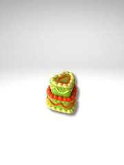 Neon-colored cake clicker in yellow, green, and orange on a white backdrop.