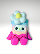3D printed kawaii spinner in rainbow pink character sitting with a daisy flower spinner on its head