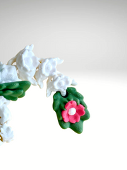 White 3D printed flower dragon charm with pink floral details and green leaf-like spots, laying flat