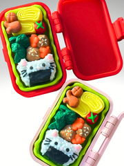 3D-printed pink and red bento box clickers opened next to each other, displaying the food-themed clickers inside each