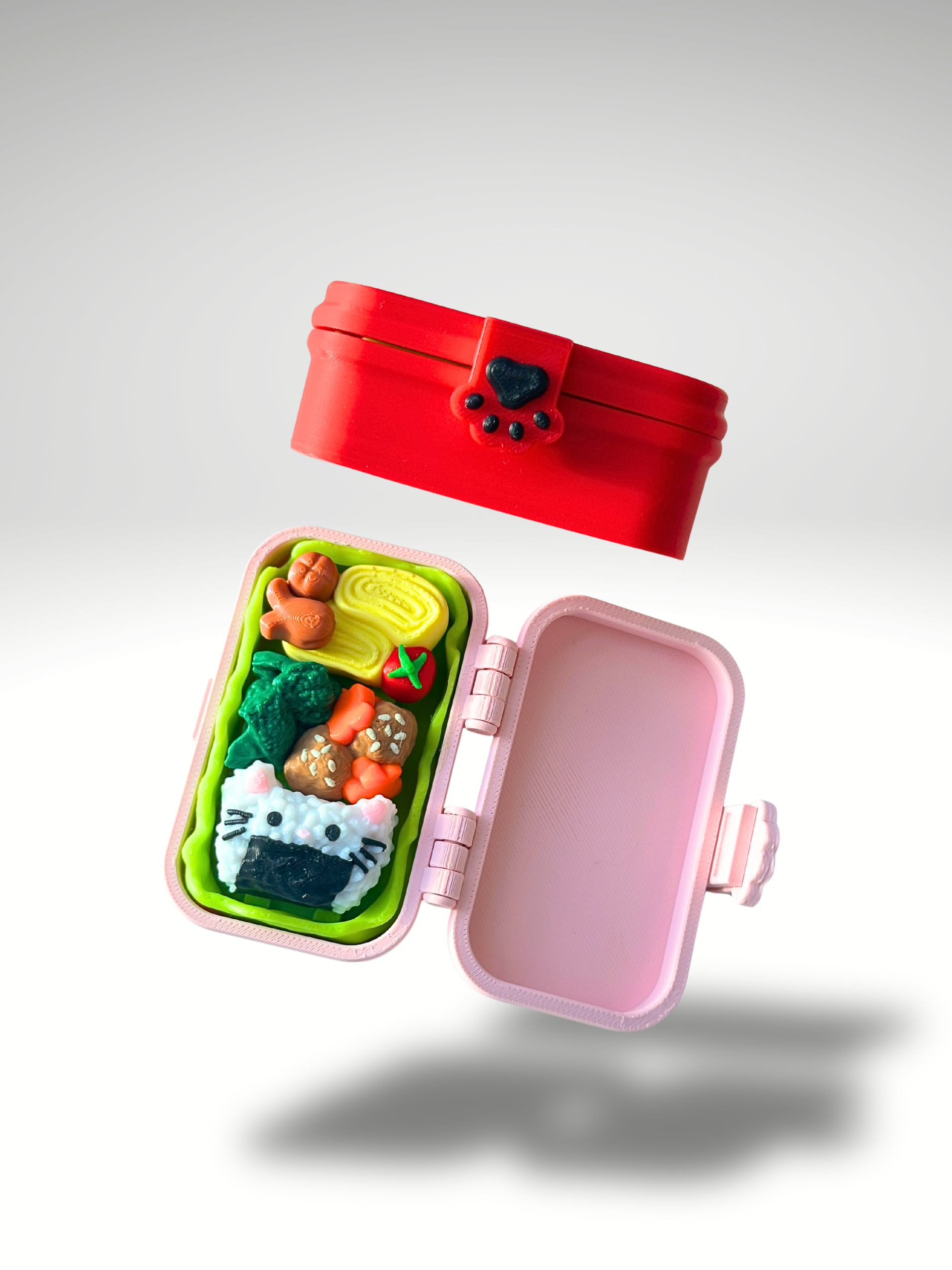 Two 3D printed bento box clicker toys shown side by side, with the red box closed and the pink box open to reveal the interior food-themed clickers