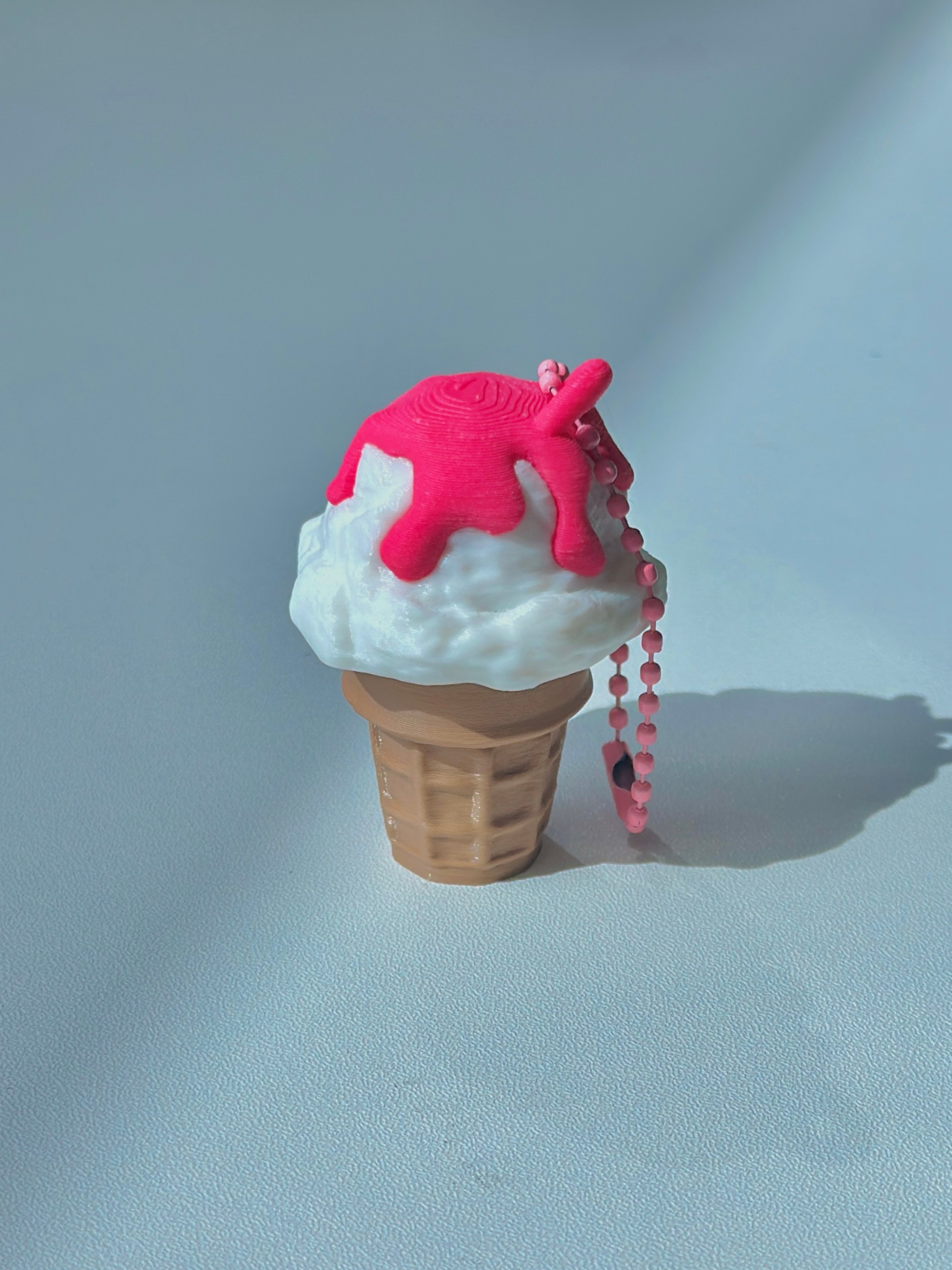 3D Printed Vanilla Ice Cream With Strawberry Sauce Cone Fidget Clicker Keychain on a table
