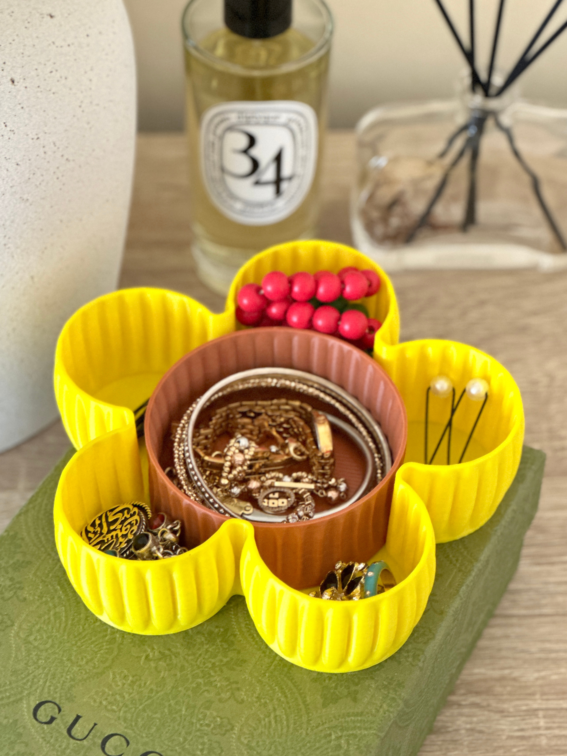 ellow 3D printed Al Samer Flower Tray placed on a table, used to hold jewelry items, showcasing its decorative and functional purpose