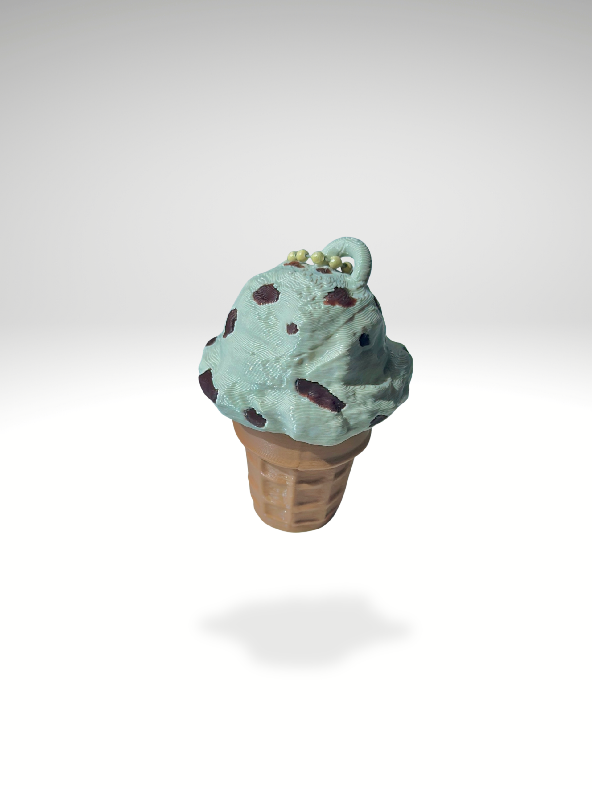 3D printed cookies and cream ice cream cone clicker with speckled cookie details on top, placed on a clean white background