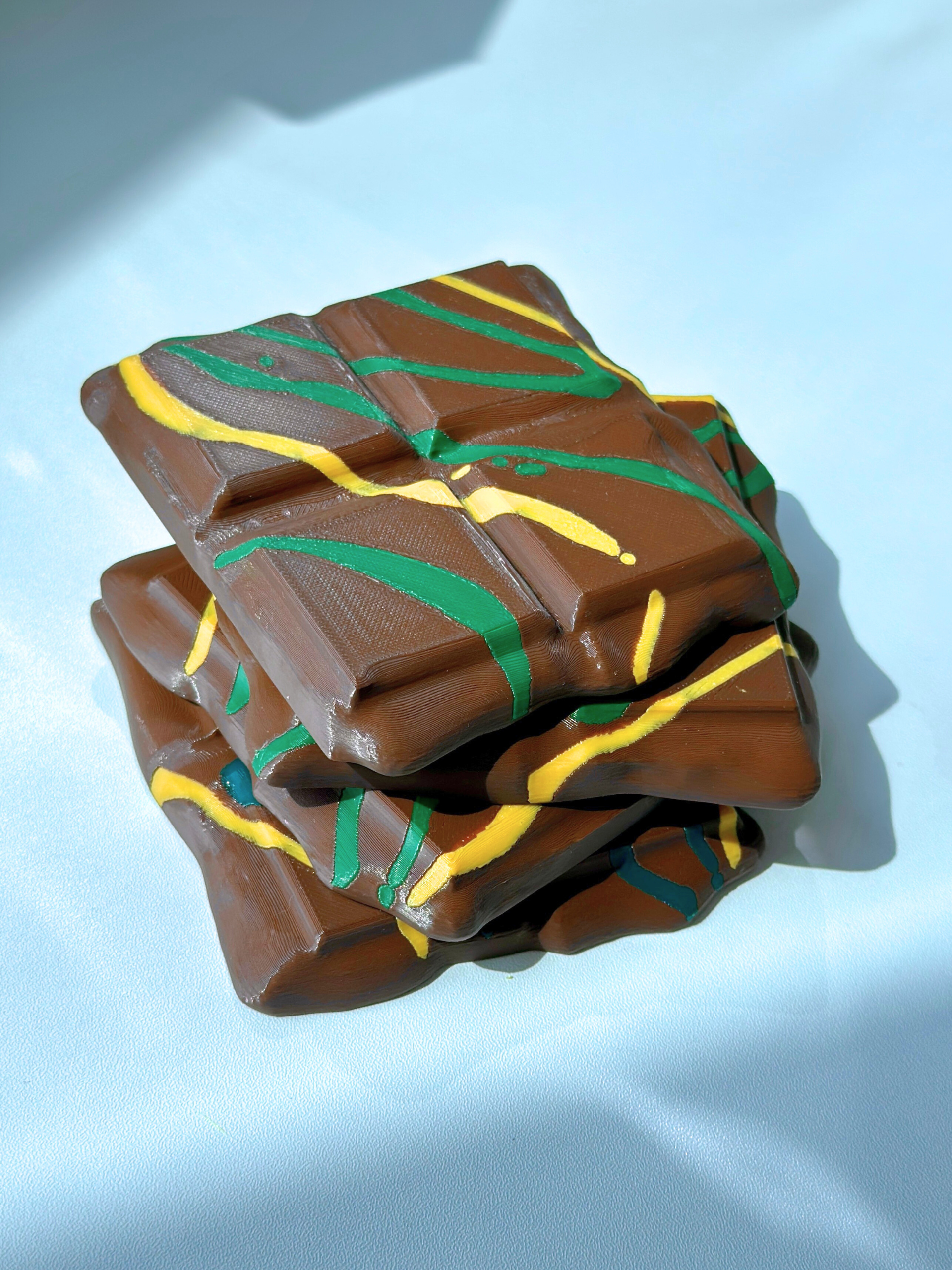 Four 3D printed chocolate drink coasters stacked together on a flat surface.