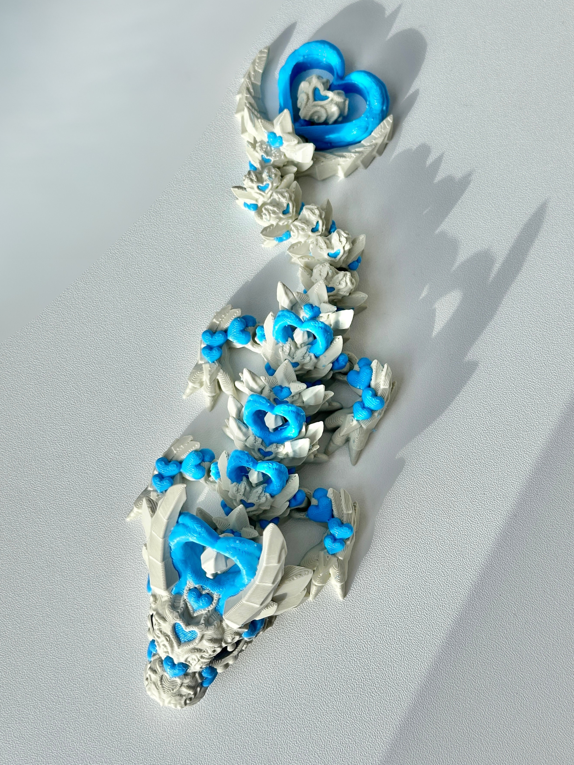 Flat lay image of 3D printed Heart Dragon in khaki-blue on a table