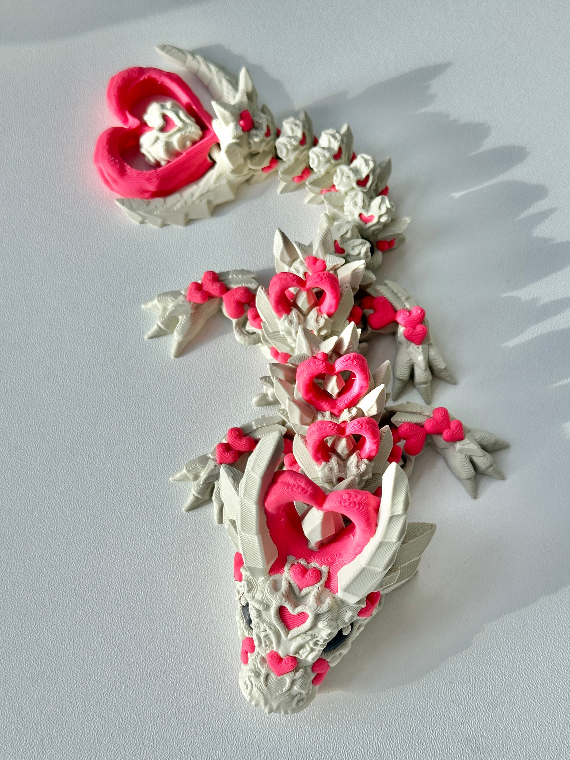 Flat lay image of 3D printed Heart Dragon in khaki-pink on a table