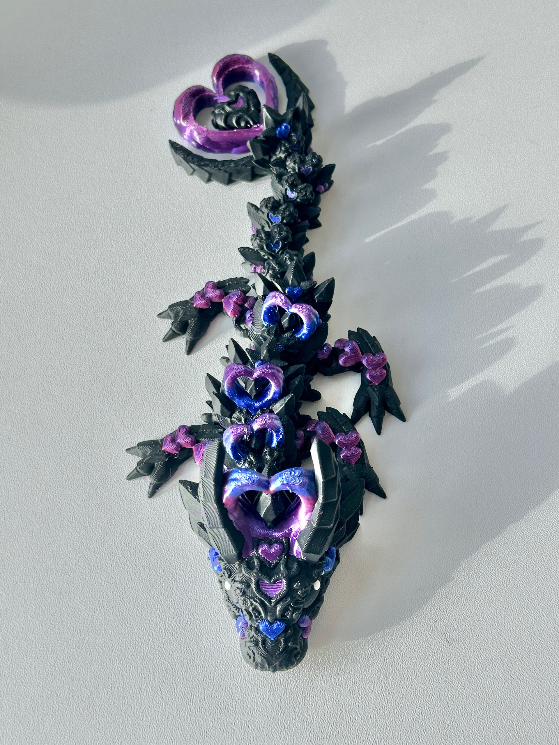 Flat lay image of 3D printed Heart Dragon in black-purple on a table