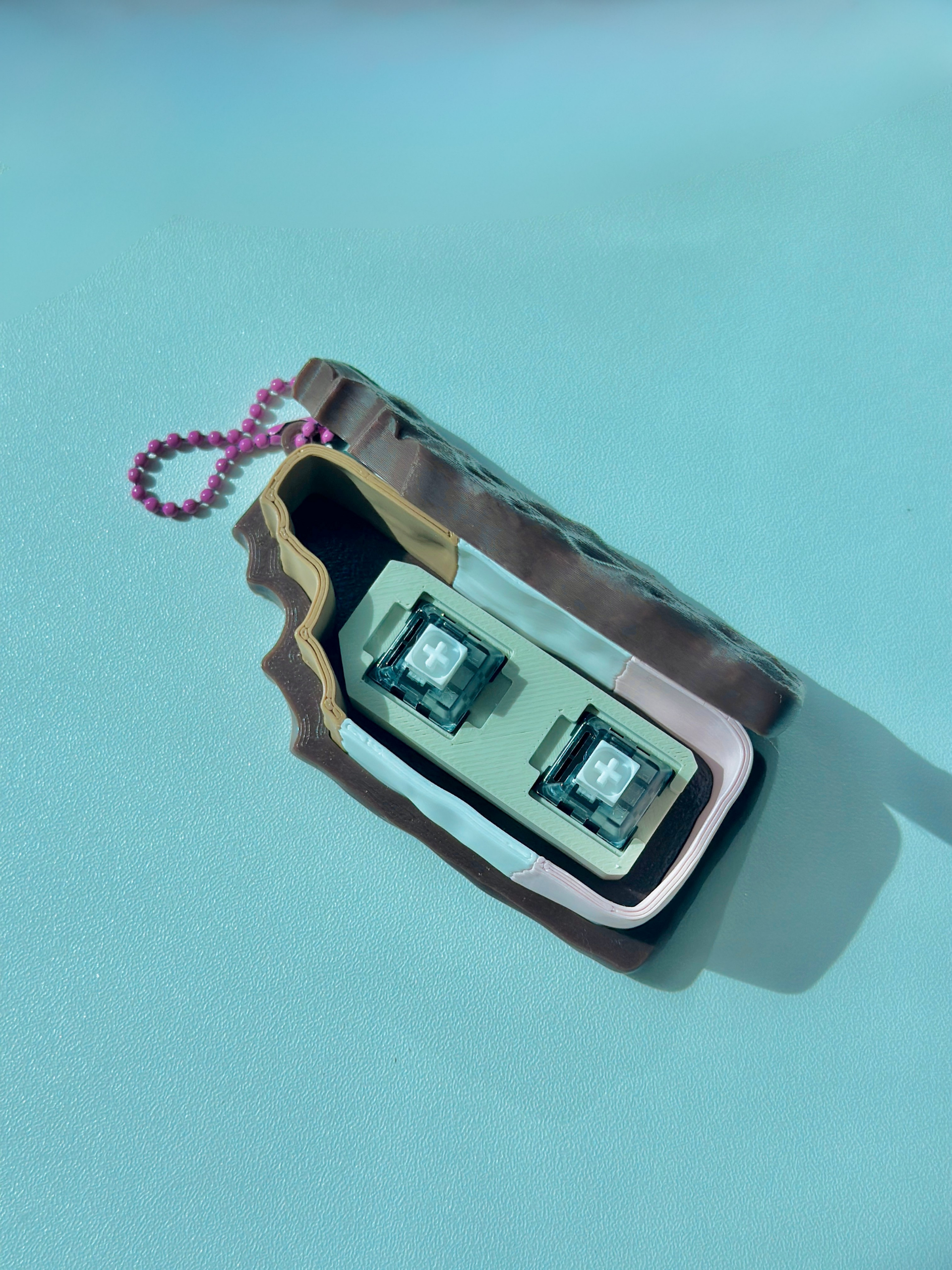 Neapolitan fidget toy keychain opened to expose two built-in click switches inside