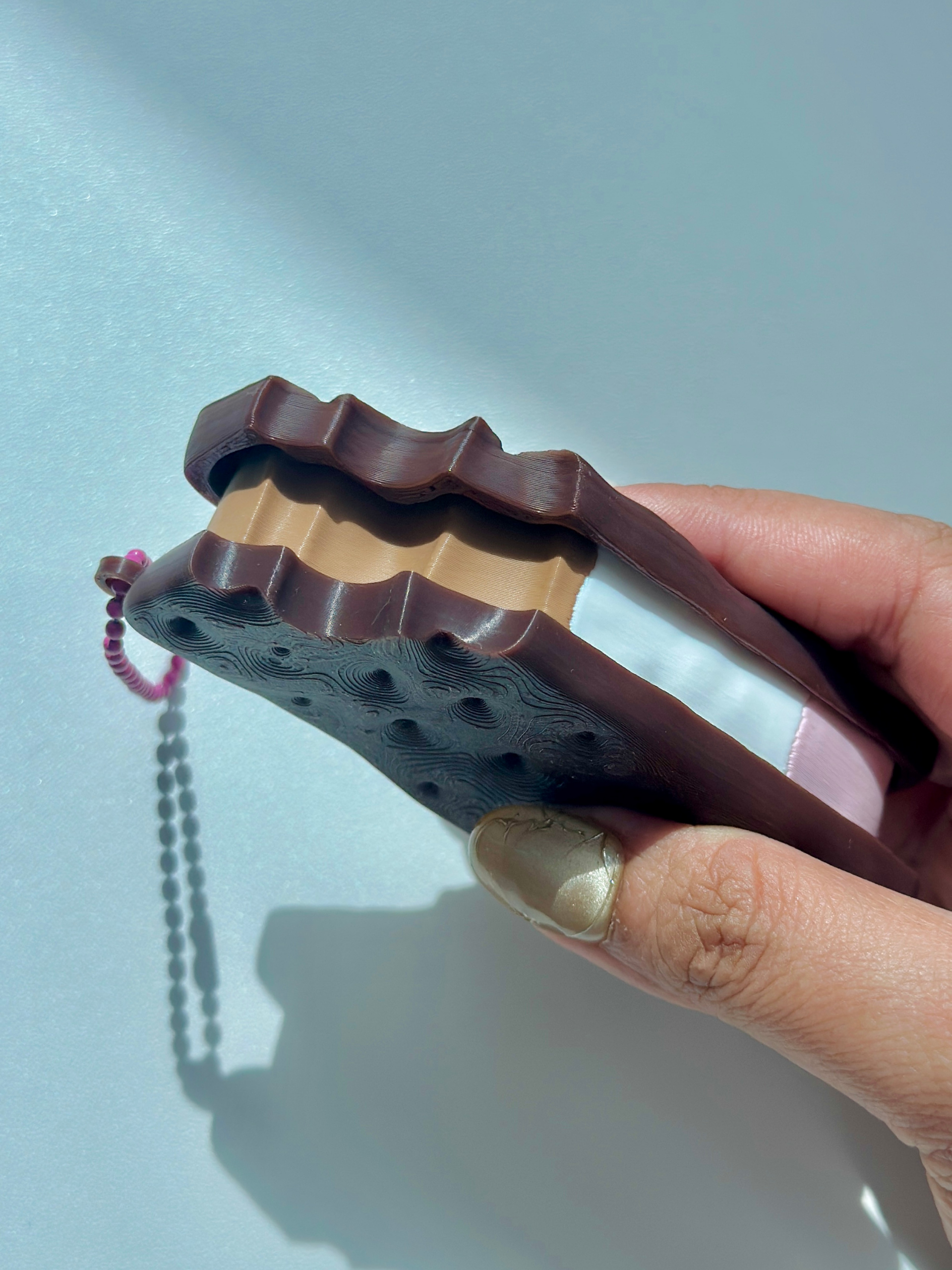 3D printed Neapolitan ice cream sandwich keychain with bite impression, held in hand, showing layered filling