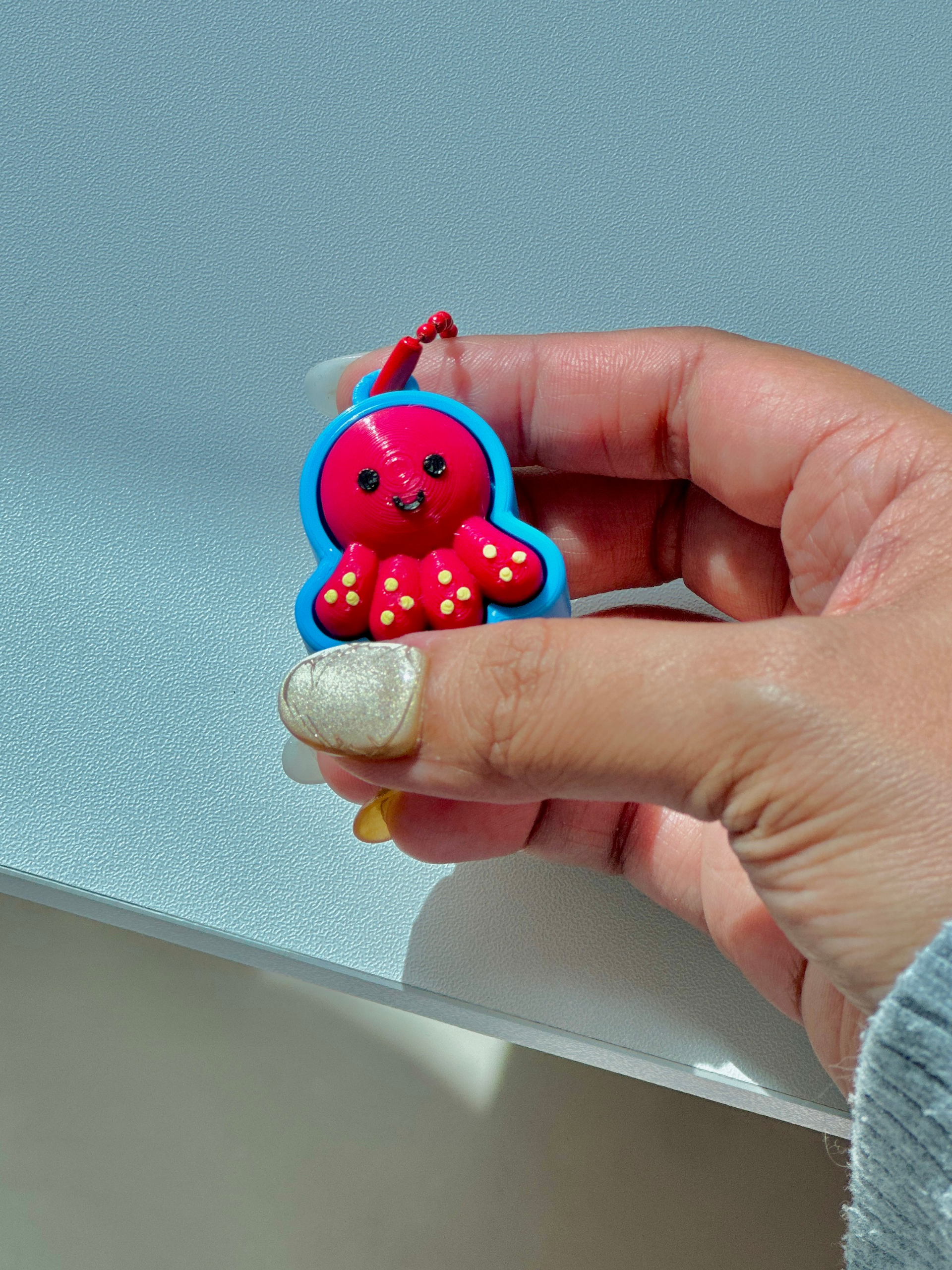 3D printed Octopus clicker keychain held in hand to show compact size and portable design