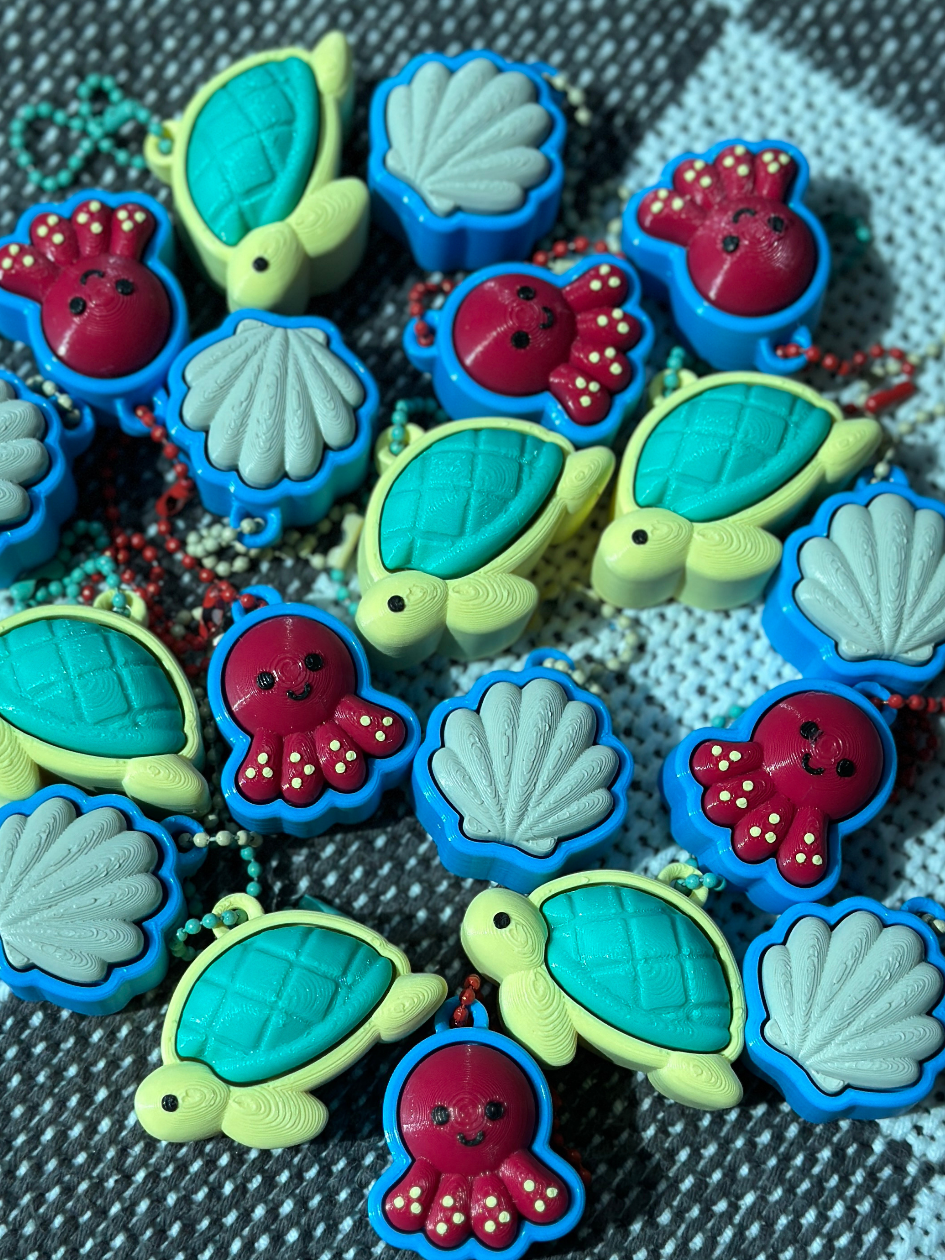 Multiple Sea Friends fidget toy keychains (turtle, shell, octopus) scattered on a surface, showing colorful ocean-themed designs