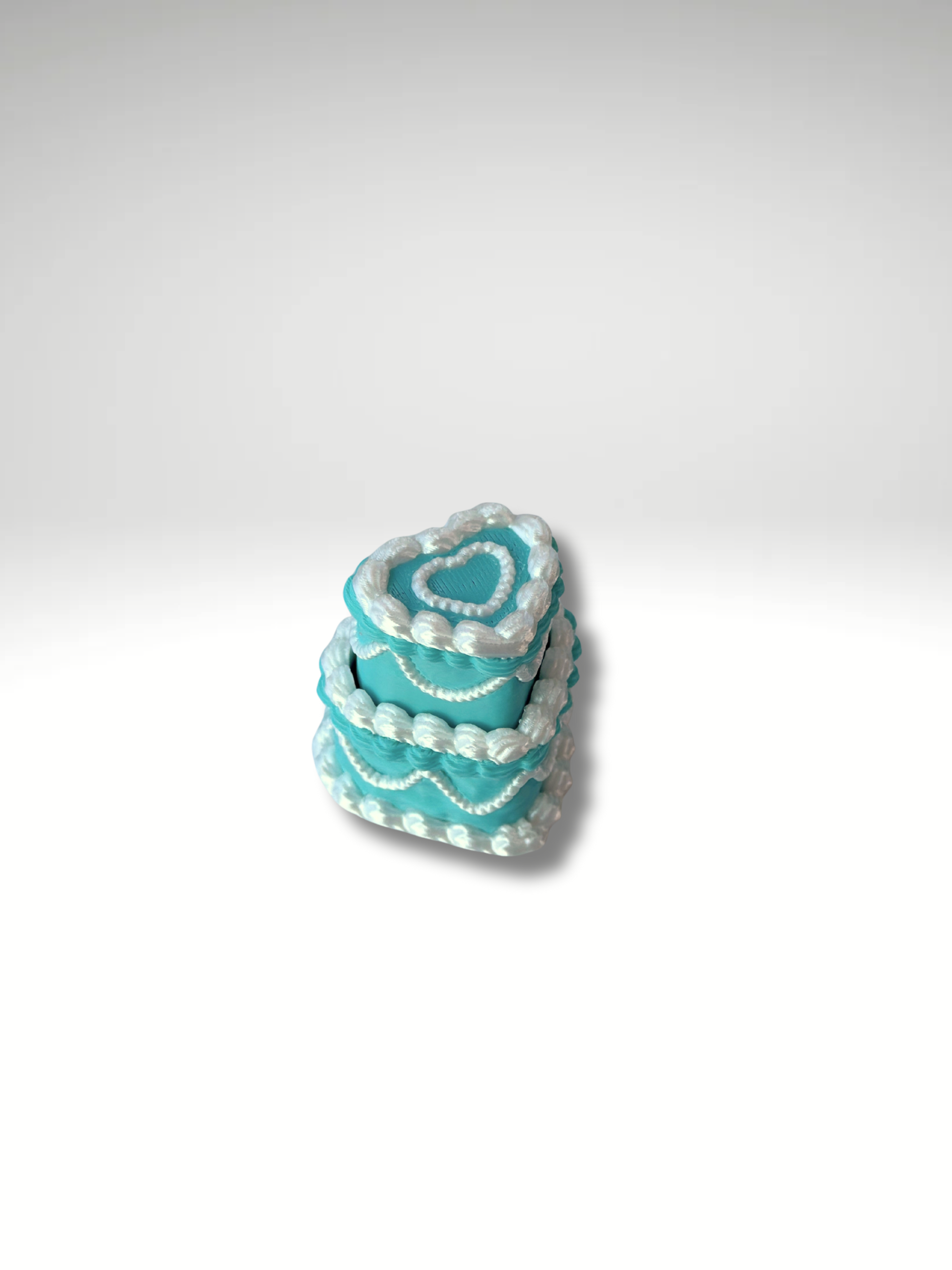 Soft teal and silky white heart cake clicker on a minimalist background.
