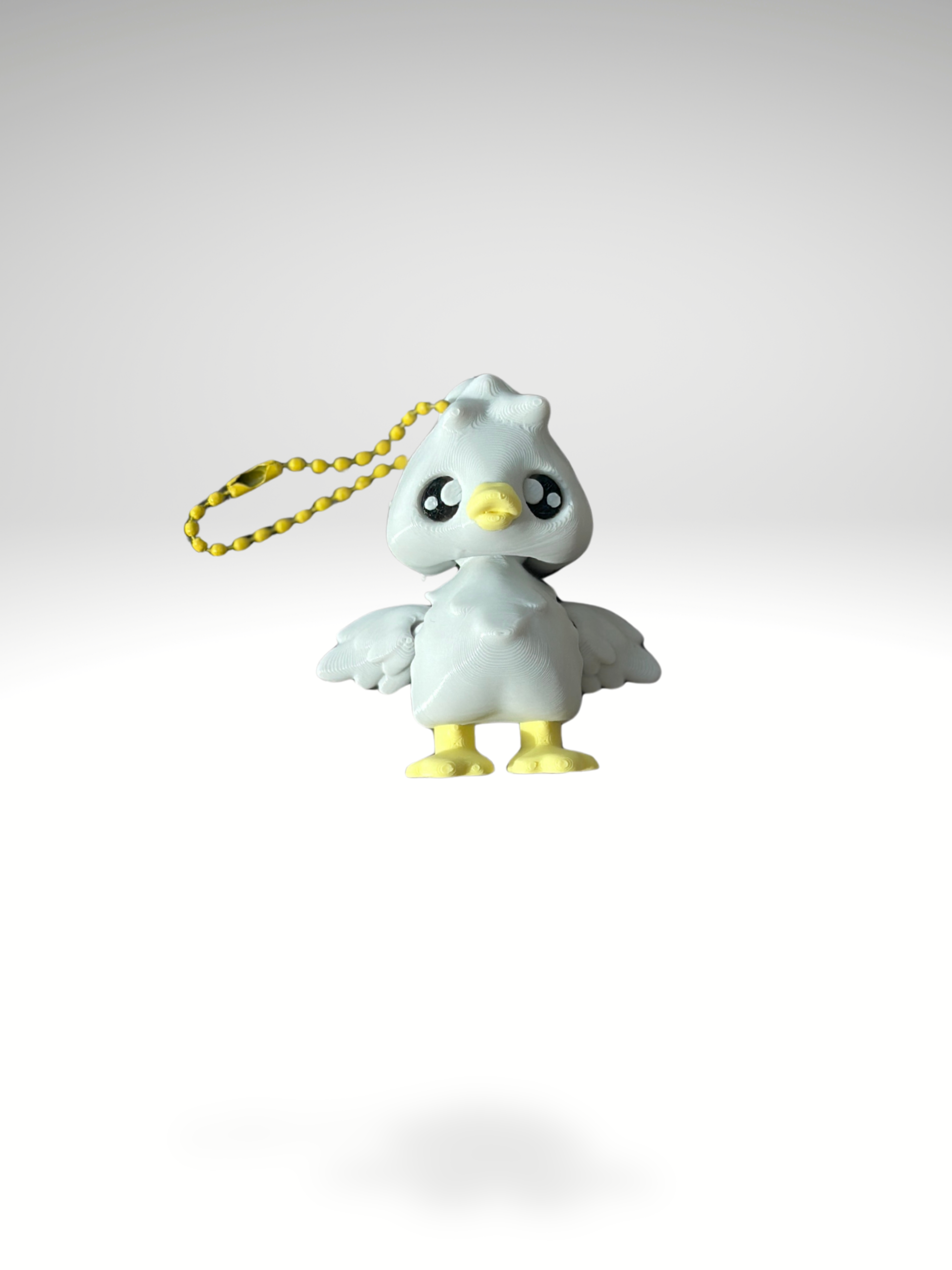 Close-up of white 3D printed goose bag charm with yellow beak and feet on a white background