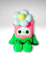 3D printed kawaii spinner in pink - green character sitting with a daisy flower spinner on its head