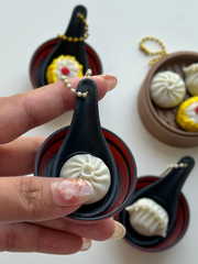 Hand holding dim sum fidget clicker keychain with Baozi on spoon in bowl Dubai